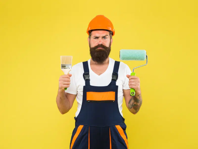 Personne avec rouleau peinture et pinceau dans les mains