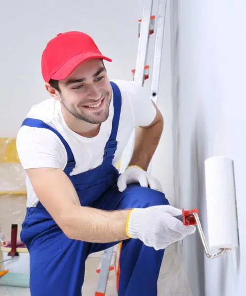 Peintre en bleu de travail avec rouleau de peinture à la main